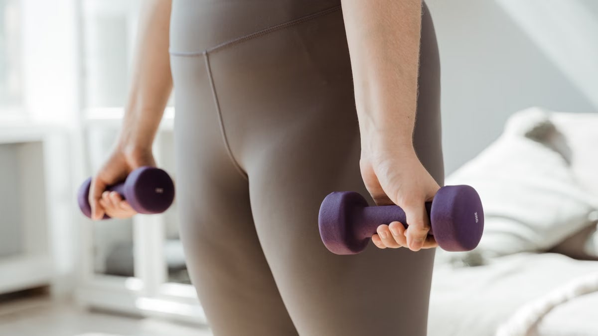 Close-up shot of a person holding purple dumbbells, symbolizing fitness and healthy living.